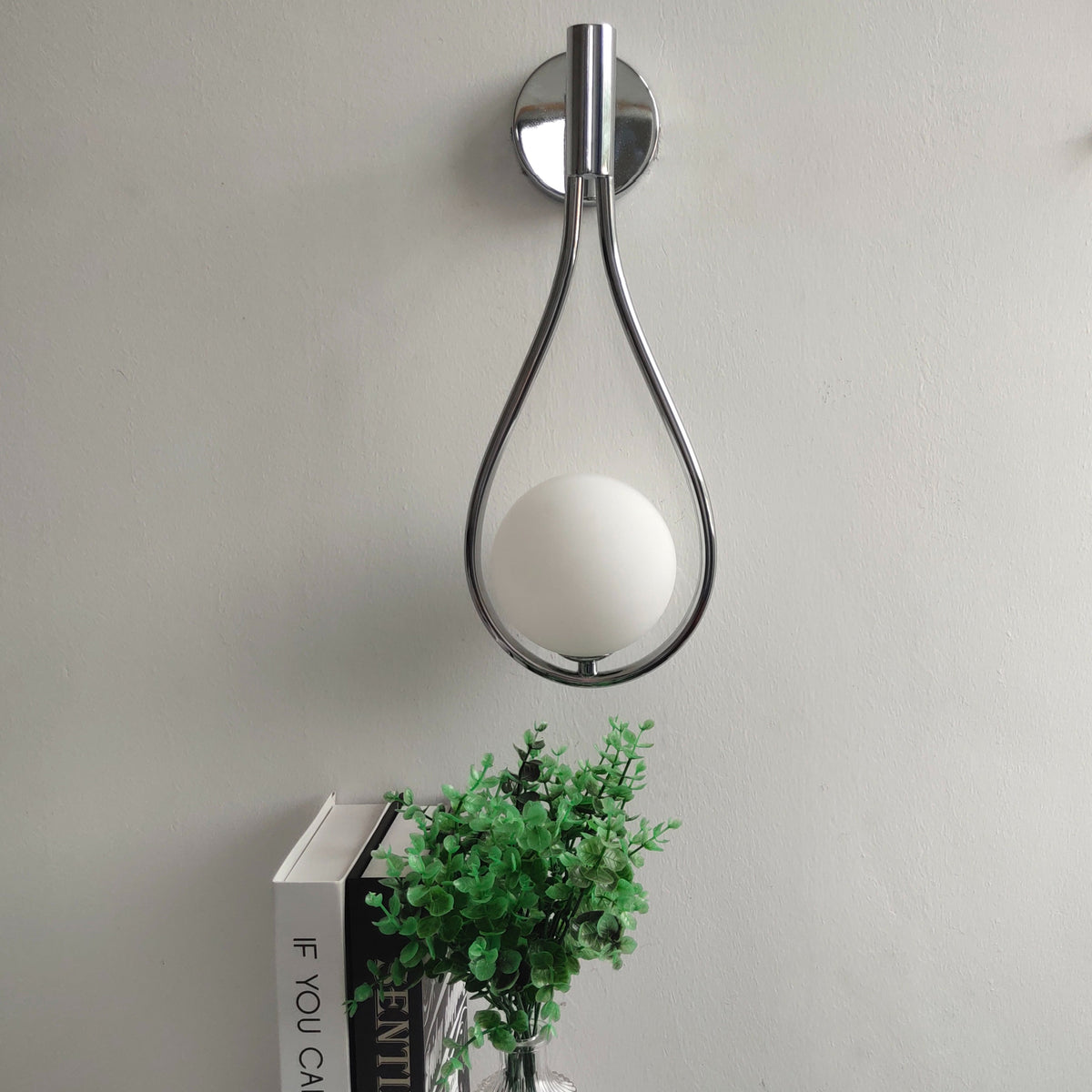 Vegglampe med frostet glasskule og dråpeformet metallramme