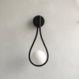 Vegglampe med frostet glasskule og dråpeformet metallramme
