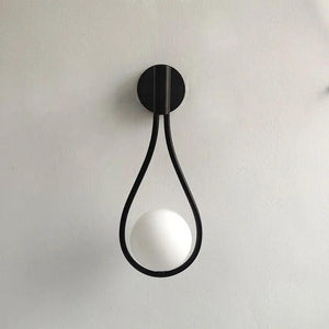 Vegglampe med frostet glasskule og dråpeformet metallramme